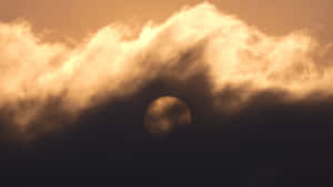 太陽部分隱藏在金色雲層後面，夕陽西下。 — iMac 壁紙