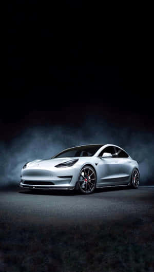 銀色Tesla Model 3在深色煙霧背景上被聚光燈照亮。