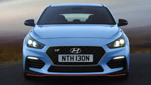 藍色Hyundai i30N跑車在山路上亮著車頭燈。