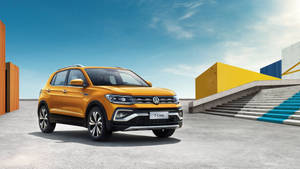 陽光明媚的日子裡，橙色福士 T-Cross SUV 停泊在色彩繽紛的現代建築附近。