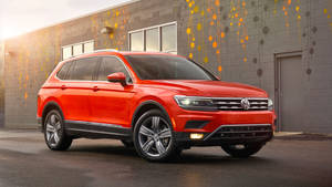 紅色福士偉根 Tiguan SUV 停在一棟現代建築前，建築上有色彩繽紛的牆壁藝術。