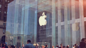 人們聚集在玻璃Apple Store外，一個大型銀色標誌反射著陽光普照的城市景觀。