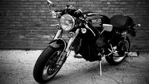 一輛Ducati電單車停在磚牆旁裂開的瀝青路面上。