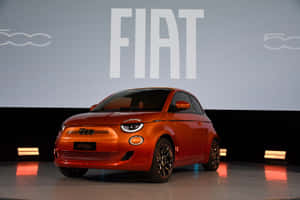 橙色Fiat 500e電動車在舞台上，後面有品牌標誌。
