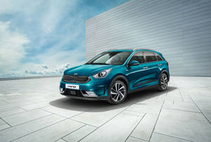 青色Kia Niro SUV停泊在屋頂上，有現代牆壁和藍天。