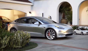 銀色 Tesla Model 3 停泊在白色灰泥房屋前，房屋有拱形門口和盆栽棕櫚樹。 — Tesla GIF 壁紙