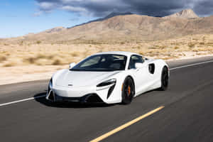 白色McLaren跑車在沙漠高速公路上飛馳，背景有山脈。