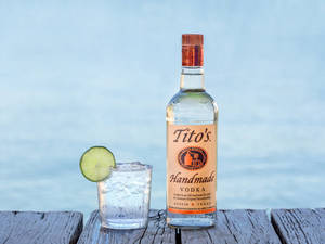 Tito's伏特加酒瓶和雞尾酒在木碼頭水邊