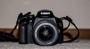 黑色Canon DSLR相機配備18-55mm鏡頭，放在灰色地毯上。