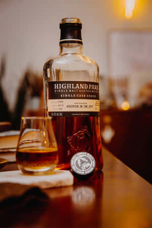 一瓶Highland Park威士忌和一個杯子放在木製吧檯上。