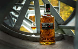 一瓶 Highland Park 威士忌旁邊放著一個玻璃杯，由金屬條和秋葉框住。