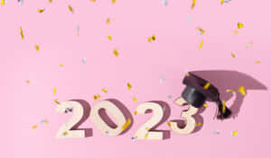 畢業帽和木製2023字母，粉紅色背景上紙屑飄落。