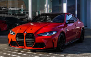 日落時分，紅色BMW M4跑車停在玻璃建築外。