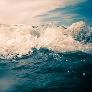 海洋波浪在多雲的天空下撞擊，帶有白色泡沫。