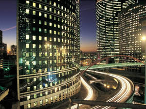 高聳的玻璃建築，亮著燈的窗戶和黃昏時發光的道路。