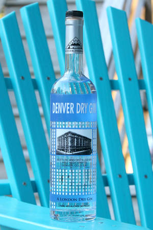 一瓶 Denver Dry Gin 放在藍色木椅上。