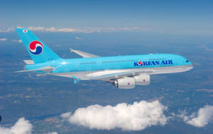大韓航空飛機在藍天和下方陸地的雲層之上飛行。