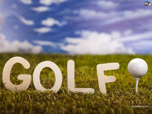 拼寫GOLF的木製字母放在草地上，旁邊是發球檯上的高爾夫球，背景是藍天。