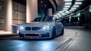 銀色BMW M3在夜間現代隧道中飄移，車頭燈發光。