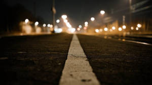 夜間道路，白色線條，模糊的街燈在前方。