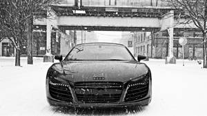 黑色奧迪R8停泊在積雪街道天橋下，雪花飄落。 — Audi R8 GIF 壁紙