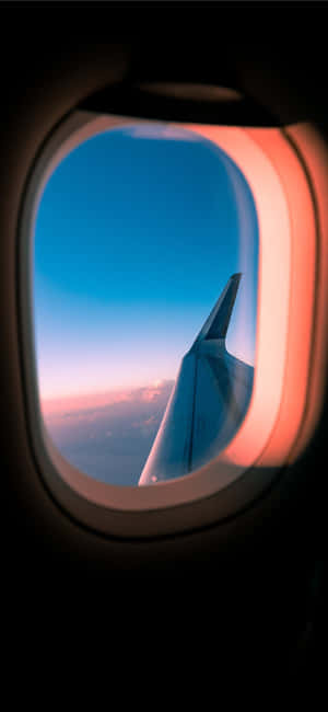 透過窗戶看到的飛機機翼，背景是日落天空 — ZTE Axon 60 Ultra 壁紙