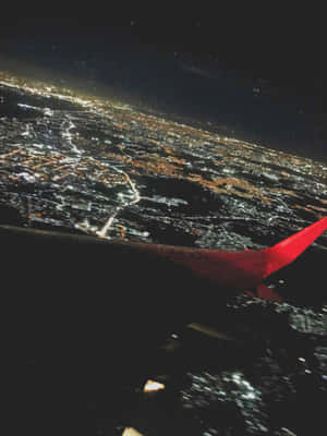 紅色飛機機翼在夜晚發光的城市上空。 — 藍天 壁紙