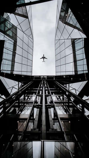 一架飛機在黑白城市景觀中，於 towering 玻璃摩天大樓之間飛行。 — 天空 壁紙