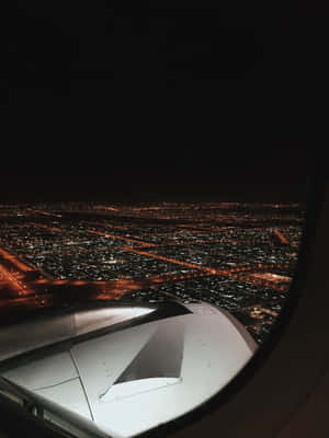 從飛機窗戶看到的夜景，顯示城市燈光和機翼 — 天空景觀 壁紙