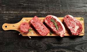 新鮮生牛肉塊以迷迭香和鹽調味，置於木板上。
