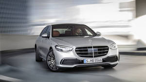 銀色 Mercedes S-Class 轎車在現代隧道中疾馳，背景模糊。