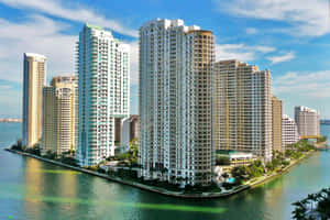 沿著運河的現代高層建築，有棕櫚樹和清澈的藍色海水。 — MacBook Air M2 壁紙