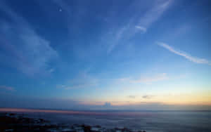 暮色天空有星星和雲朵，平靜的海洋與岩石海岸。 — 藍天 壁紙