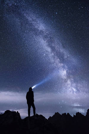 人在山頂上將手電筒照向星空