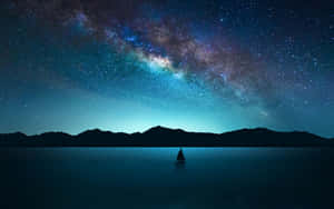 一艘帆船漂浮在平靜的湖面上，在燦爛的星空下，銀河清晰可見。 — 星星 壁紙