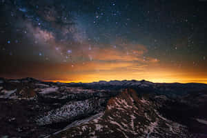 在銀河和橙色地平線下的星空雪覆蓋的山脈 — 銀河 壁紙