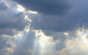 陽光光束穿過黑暗的暴風雲，在戲劇性的天空中綻放。 — 藍天 壁紙