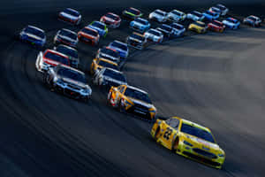NASCAR賽車在日落時分沿彎曲賽道飛馳。