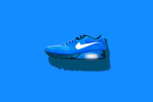 純藍色背景上，帶有發光鞋底的藍色 Nike Air Max 運動鞋。