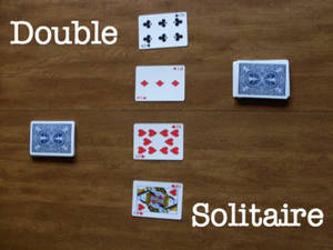 四張啤牌在木質表面上為接龍遊戲擺放，帶有「Double Solitaire」文字。