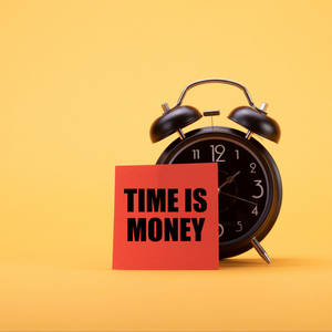 黑色鬧鐘旁邊有一張紅色卡片，上面寫著 time is money，背景為黃色。