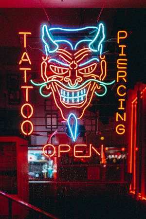 紋身和穿孔店的霓虹燈牌，惡魔面孔在夜晚發出紅藍光芒。