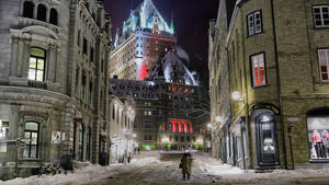 夜晚，一個人在積雪的城市街道上走向燈火通明的歷史建築。