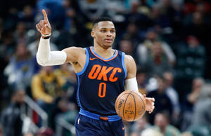 身穿OKC球衣的籃球運動員在比賽中拿著球並向上指。