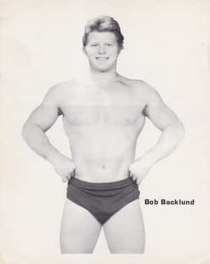 摔角手 Bob Backlund 穿著短褲，在復古照片中雙手叉腰擺姿勢。 — 摔角 GIF 壁紙