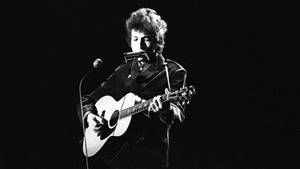 Bob Dylan 在黑白舞台上彈結他和口琴。 — 黑白 壁紙