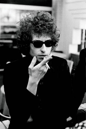 Bob Dylan 戴住太陽眼鏡喺黑白相入面食煙。