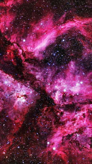 在深空中充滿發光星星的鮮豔粉紅色和紫色星雲。 — iPhone 粉紅美學 壁紙
