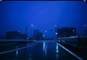雨夜的城市橋樑，發光的街燈在濕漉漉的路面上反射。 — 美學深藍 壁紙