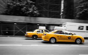 黃色的士在單色背景下於城市街道上疾馳，呈現動態模糊效果。 — MacBook Pro M1 壁紙